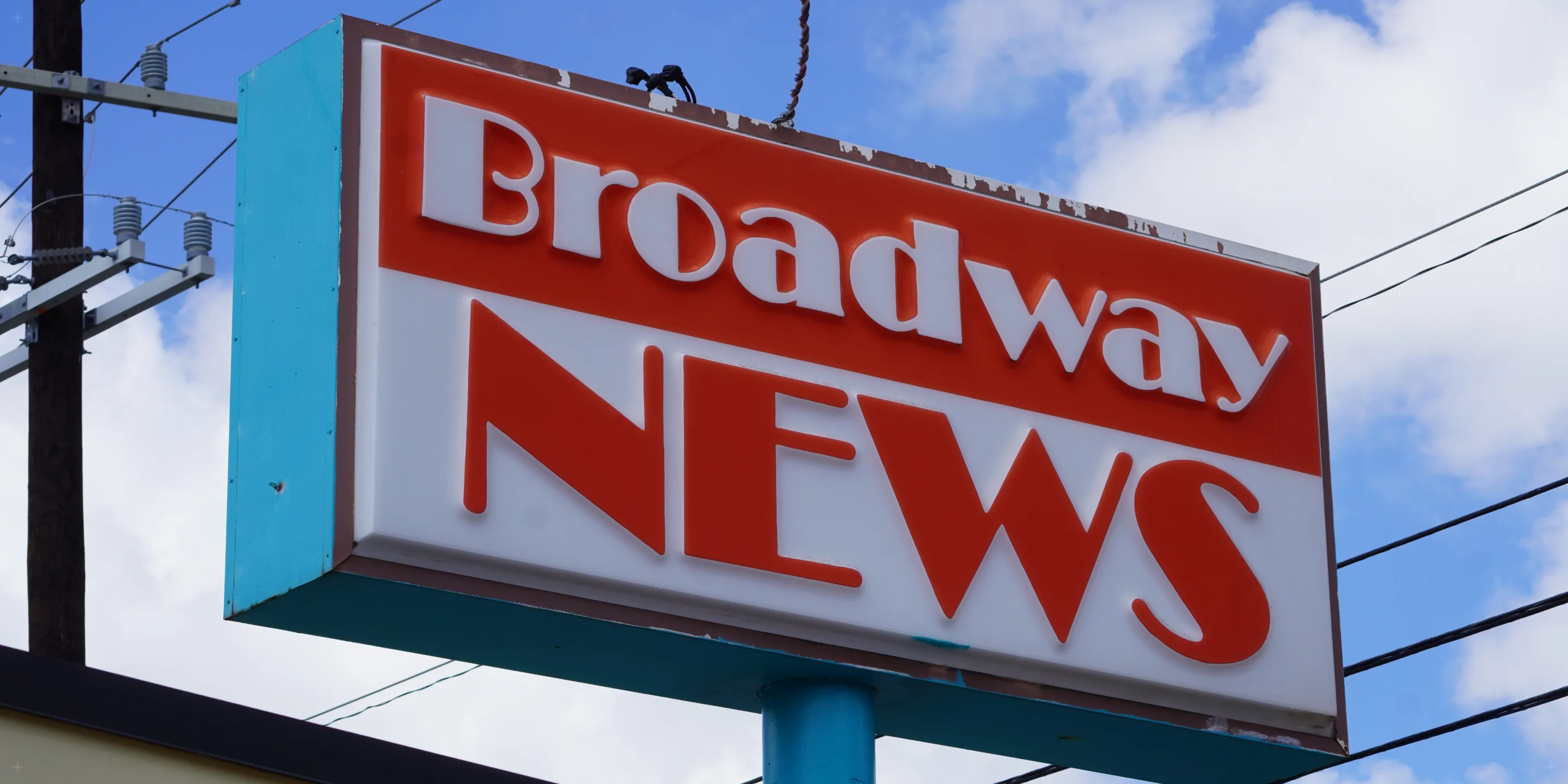 The vintage Broadway News marquee sign against a blue sky