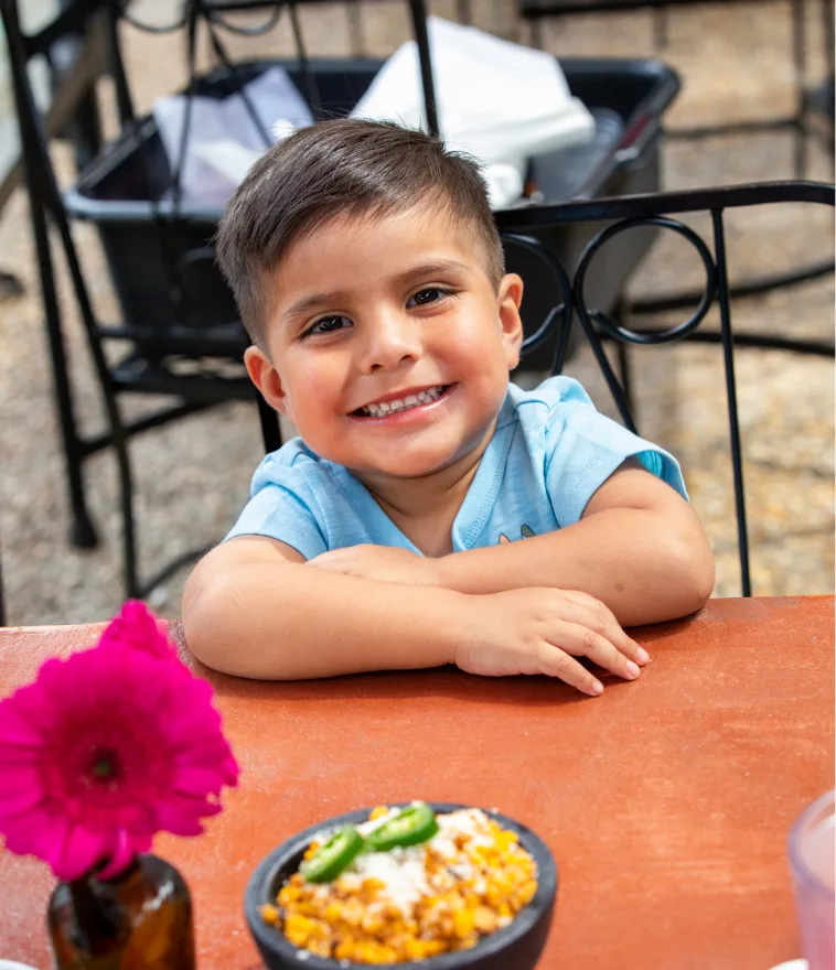 A young guest smiling at a Casa Rio patio table